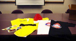 Devo artifacts, including t-shirts, vintage stickers, and an "energy dome" hat.