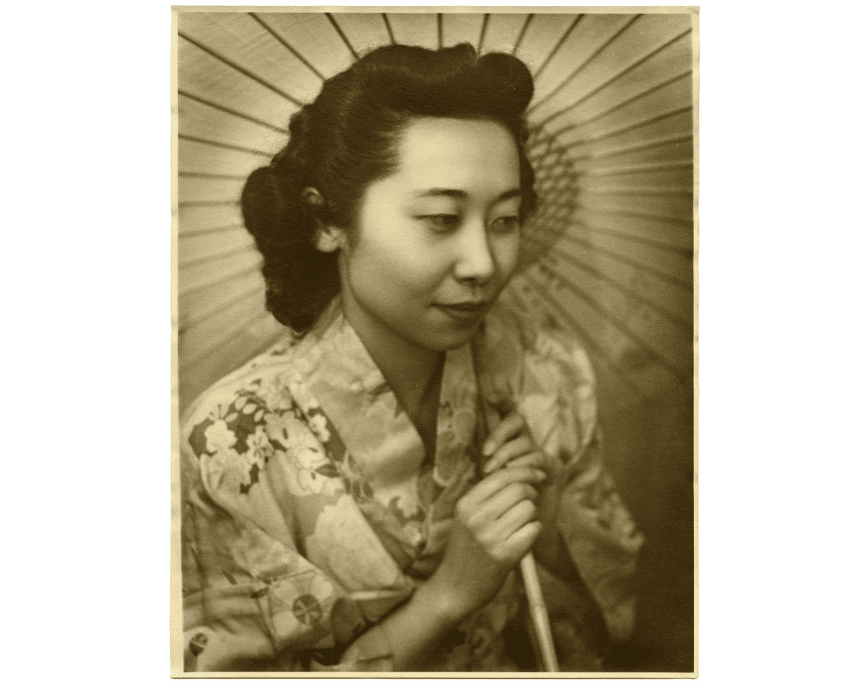 This photograph shows Japanese American Mae Takasugi with a parasol, taken in 1943 by Charles Buxton in Alliance, Ohio