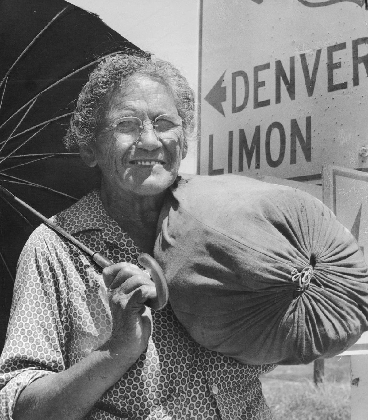 Gatewood, smiling, stands with her pack and an umbrella
