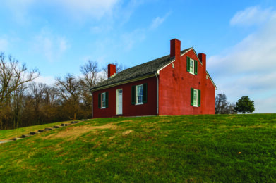 Image of the John Rankin House, a brick building on a hill with grass and blue sky in the background.