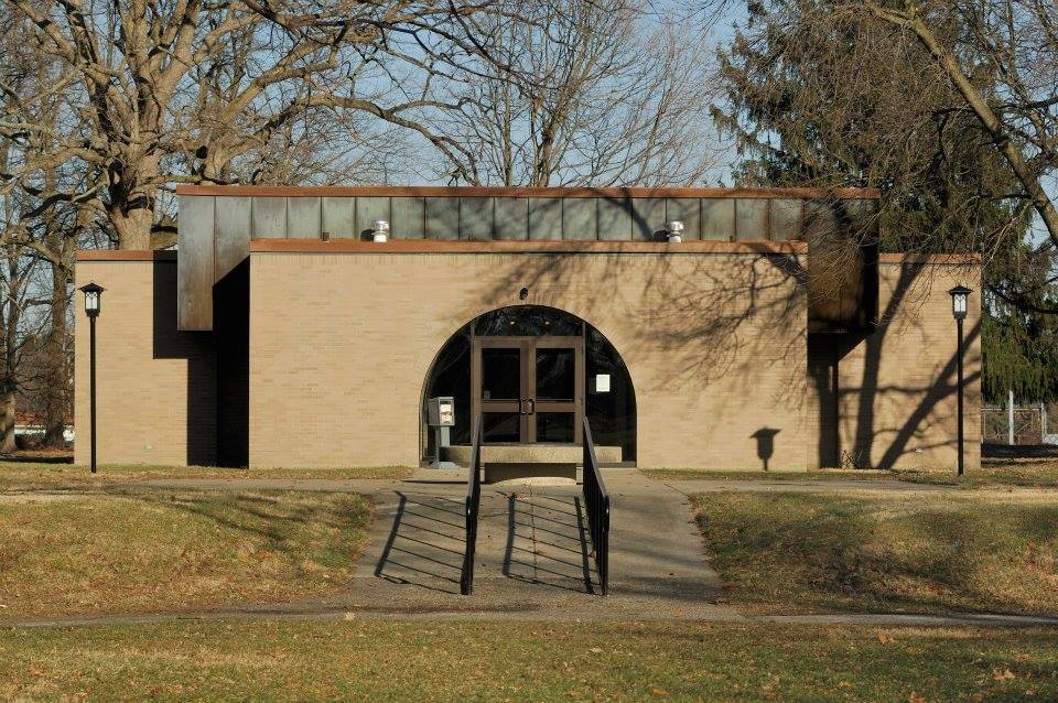 Square brick building centered with a paved walkway in front