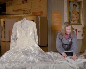 History Curator Becky Odom demonstrates how to pad the fold of a wedding dress.