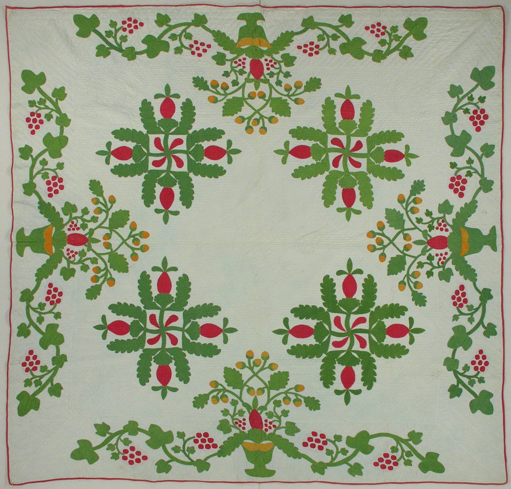 Red and green applique quilt in a pineapple swastika pattern