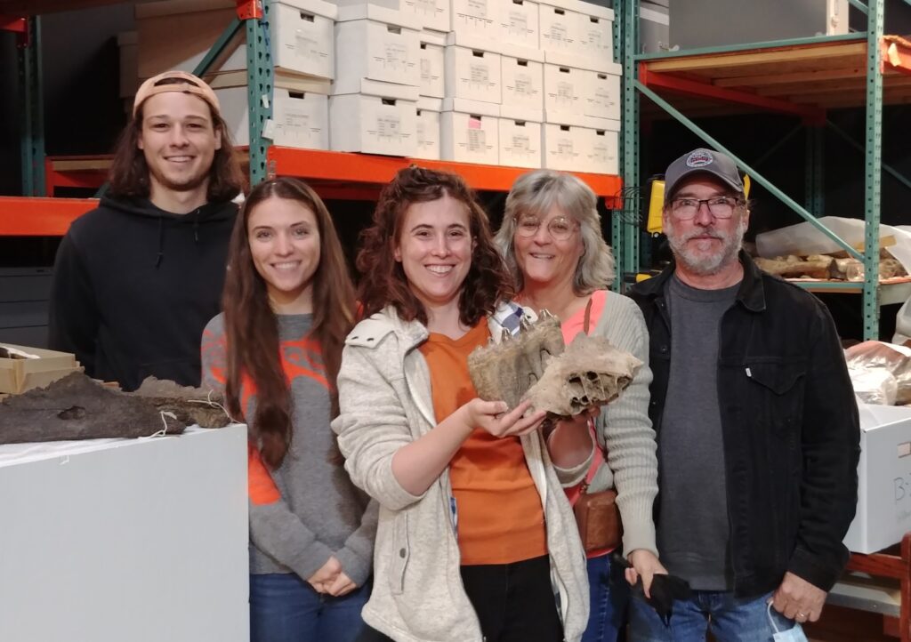 Emily George holding a tooth from the Williams mastodon. Sher is surrounded by her family.