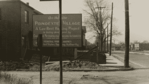 Black and White photo of an old sign at Poindexter Village that says: On this site Poindexter Village A Low-Rent Housing Project is being developed by Columbus Metropolitan Housing Authority