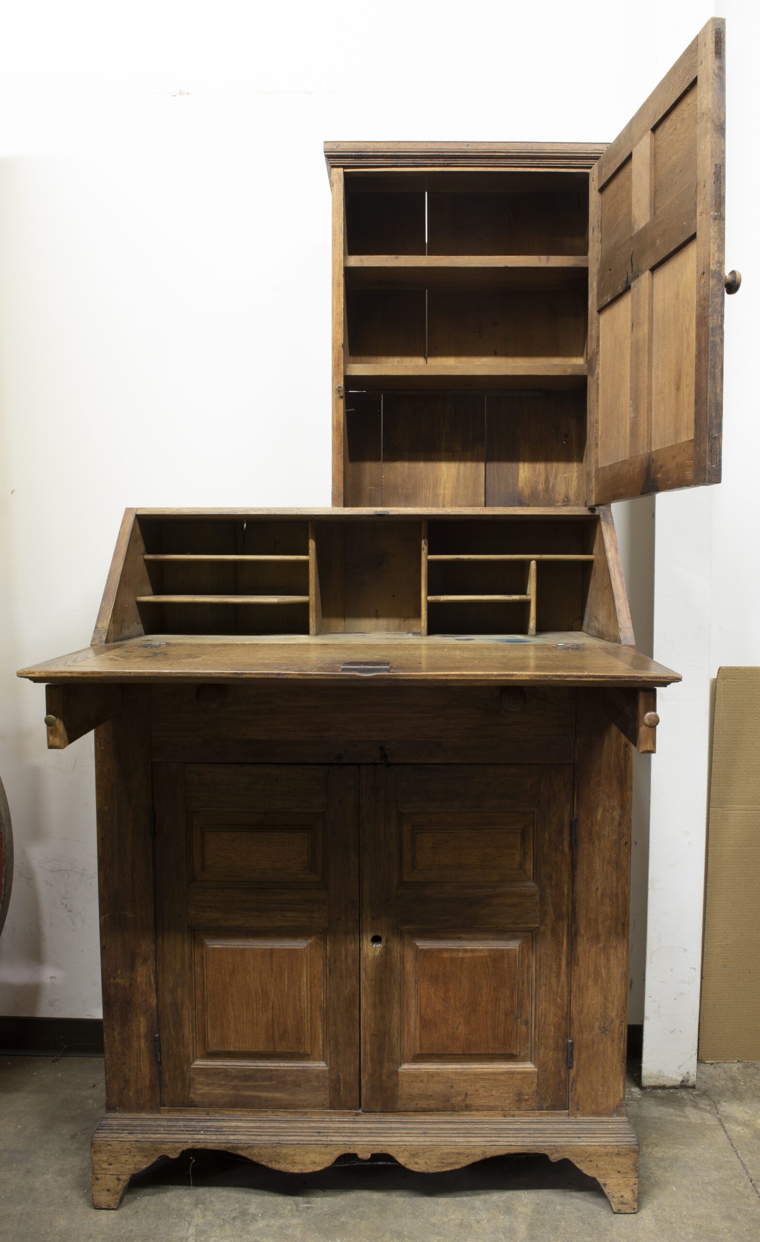 Photo of a wooden drop-front desk with a half cabinet on the top right. The cabinet door and drop front are open.