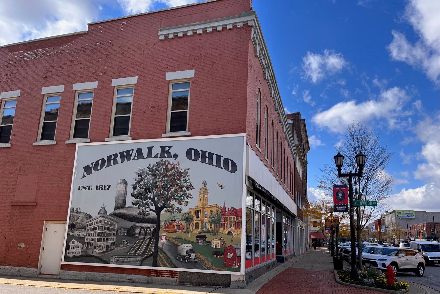 The corner of a two-story brick building has a mural of how the town looked in 1817 and how it looks today.