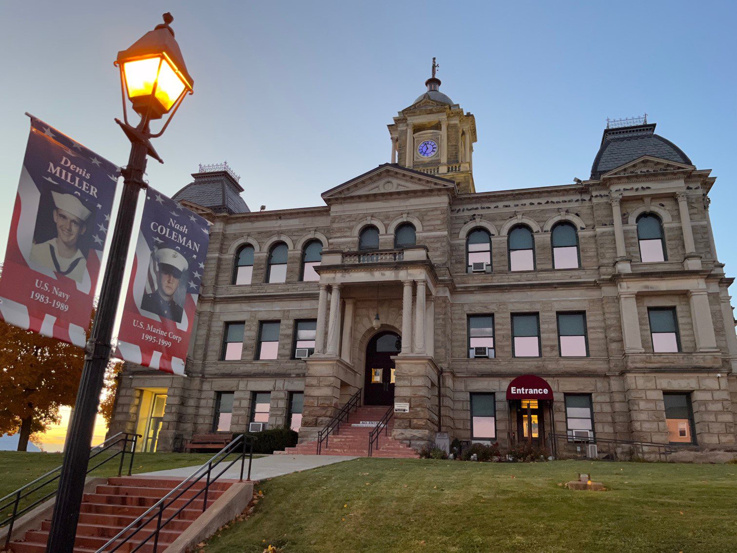 Outdoor image of a large building with a sign nearby that commemorates local war heroes.