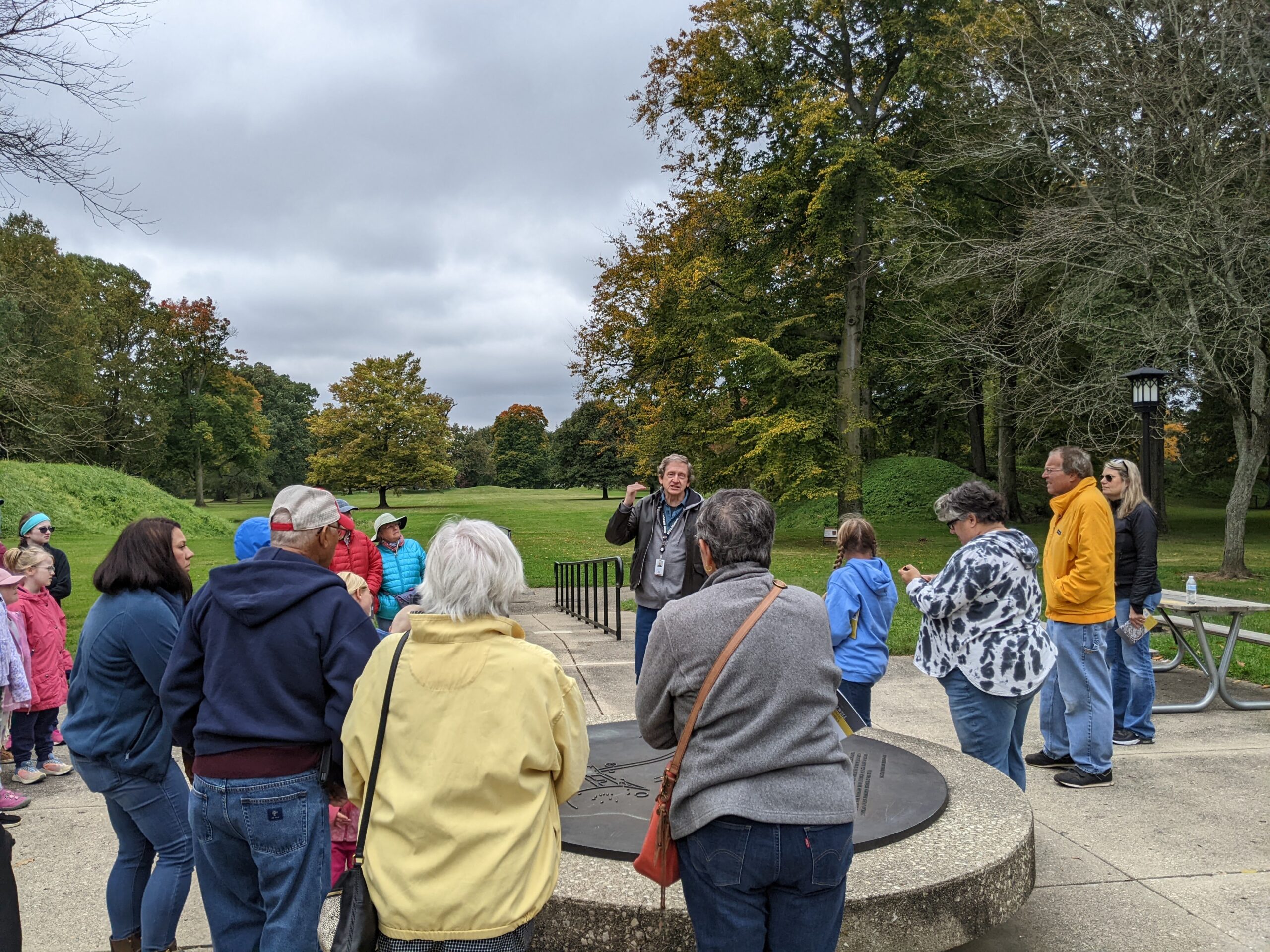 Group of people surrounding tour leader Brad Lepper at Great Circle site.