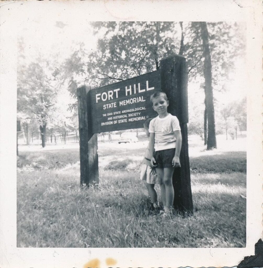 Black and White image of two children standing in front of the Fort Hill Entrance Sign. The sign says: Fort Hill State Memorial, The Ohio State Archaeological and Historical Society Division of State Memorials