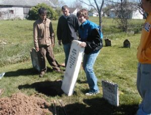 students replacing a grave marker