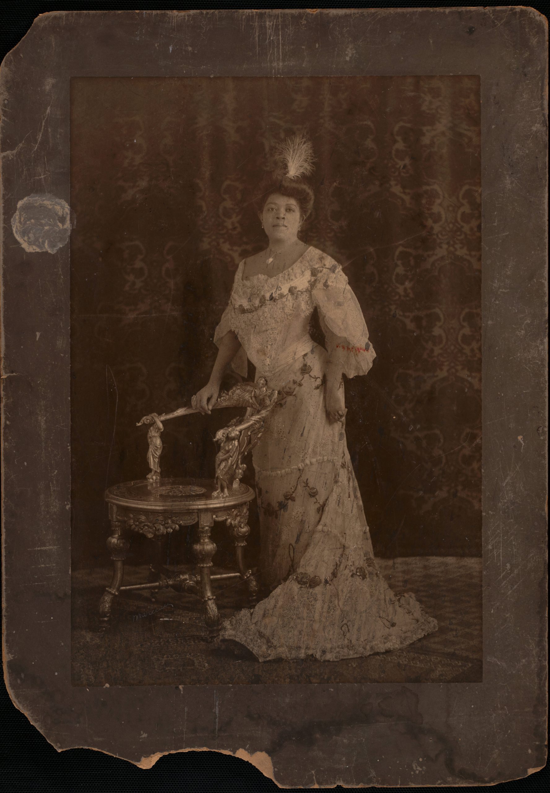 Black and white photo showing a woman in an evening gown in the 1890s.