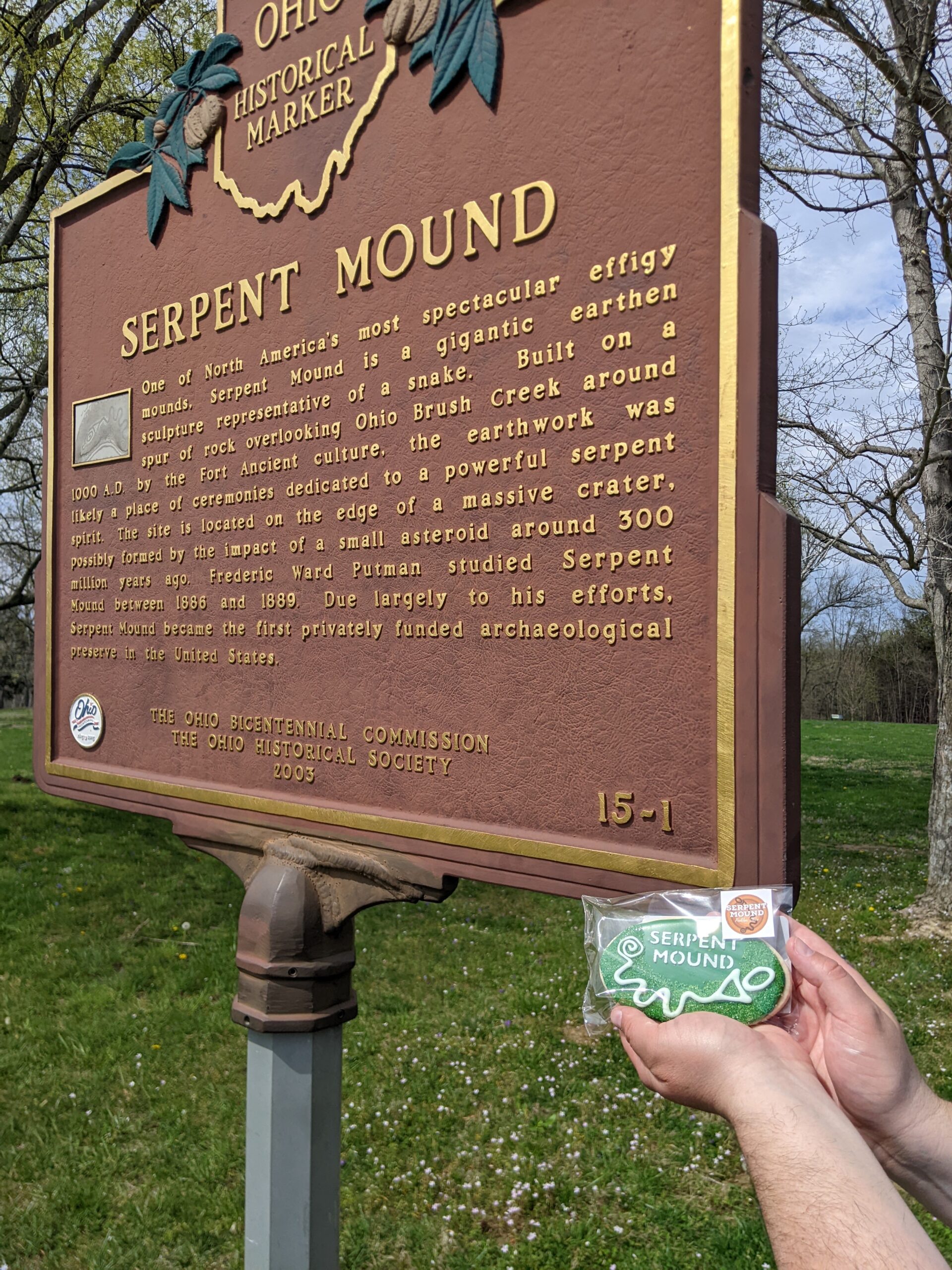 Ohio Historical Marker - Serpent Mound - One of North AMerica's most spectacular effigy mounds. Serpent Mound is a gigantic earthen sculpture representative of a snake. Built on a spur of rock overlooking Ohio Brush Creek around 1000 AD by the Fort Ancient culture, the earthwork was likely a place of ceremonies dedicated to a powerful serpent spirit. The site is located on the edge of a massive crater, possibly formed by the impact of a small asteroid around 300 million years ago. Frederic Ward Putman studied Serpent Mound between 1886 and 1889. Due largely to his efforts, Serpent Mound became the first privately funded archaeological preserve in the United States.