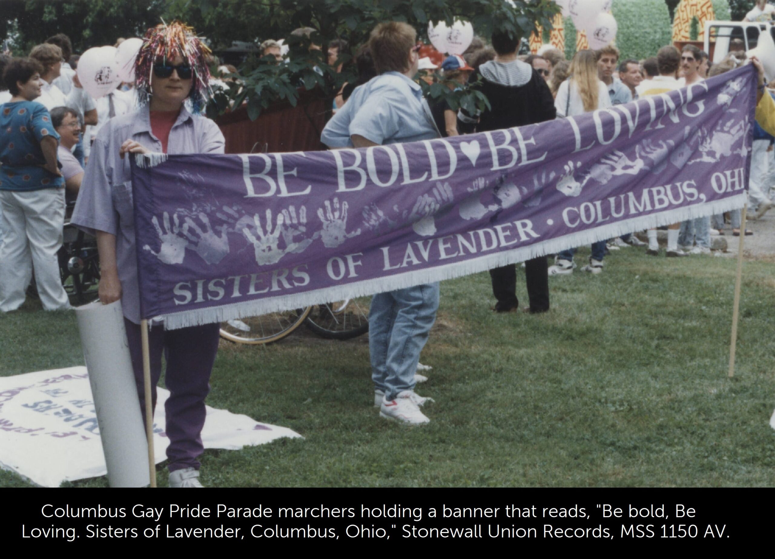 A photo of Gay Pride marchers holding a banner that reads, "Be bold, Be Loving. Sisters of Lavender, Columbus, Ohio."