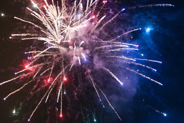 Bright white, blue and red fireworks in a dark night sky