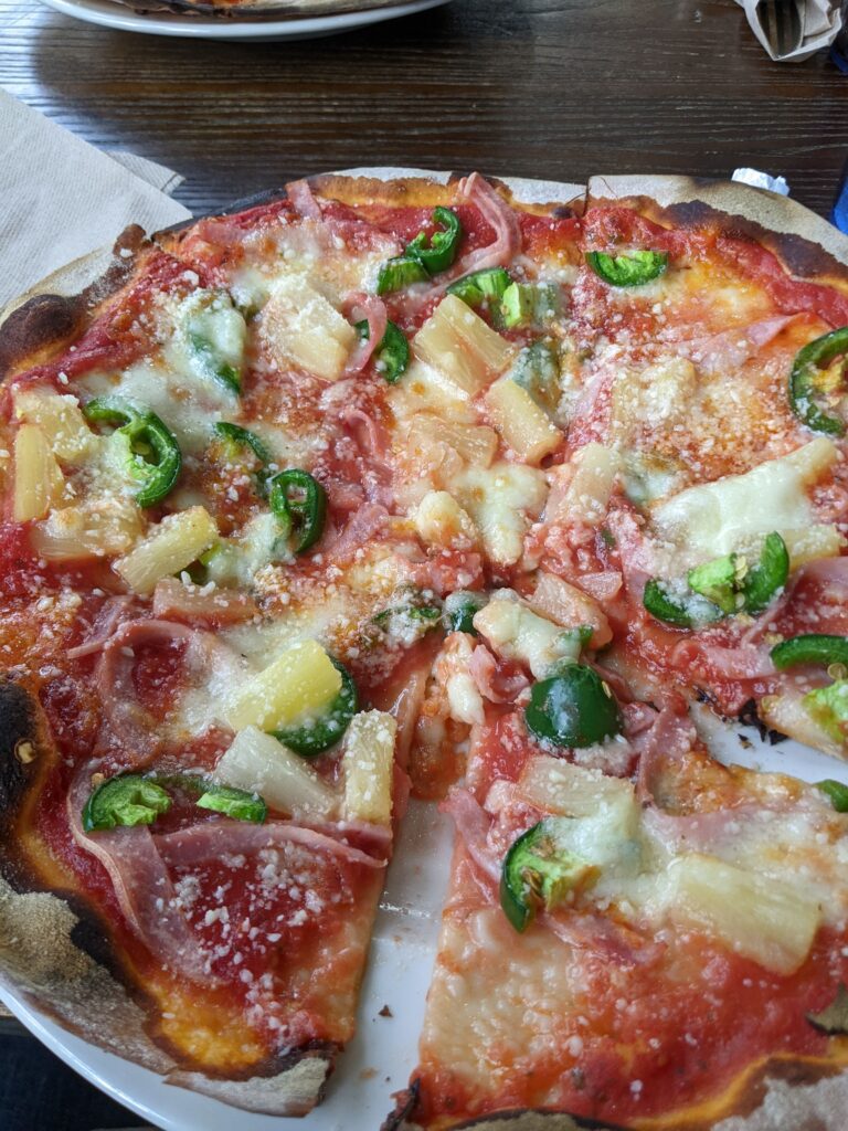 Picture of a pizza with pineapples, peppers, and ham