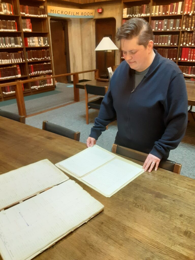 A person standing in front of a table looking over old documents.