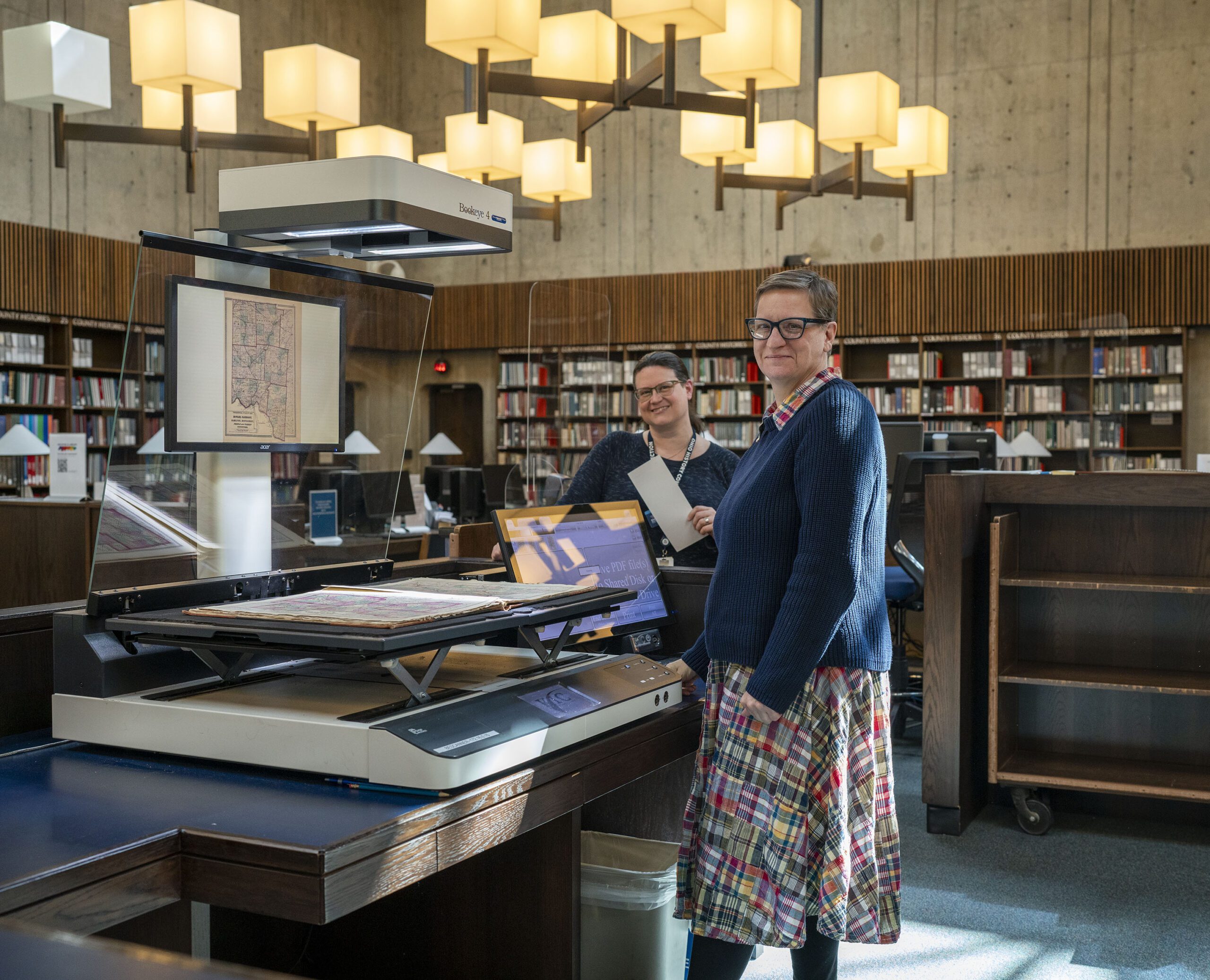 Image of the scanning equipment in the library with two individuals standing around it.