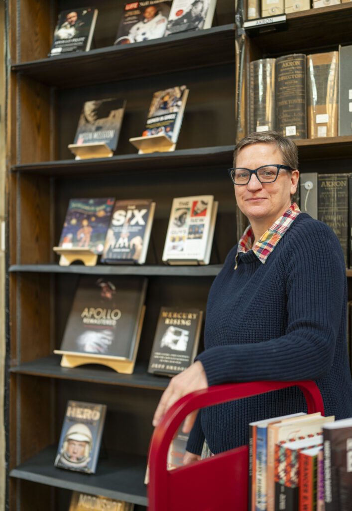 A person standing in front of a shelf of displayed books.