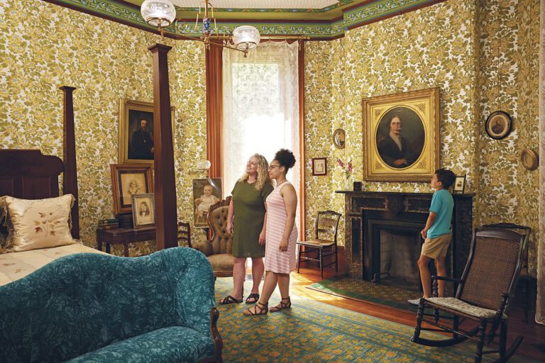 Image of two women and a child exploring a bedroom in the Hayes Home.