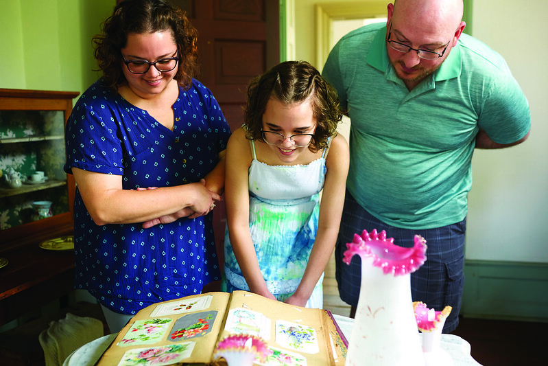 Image of a man, woman, and girl viewing artwork in Zoar Village