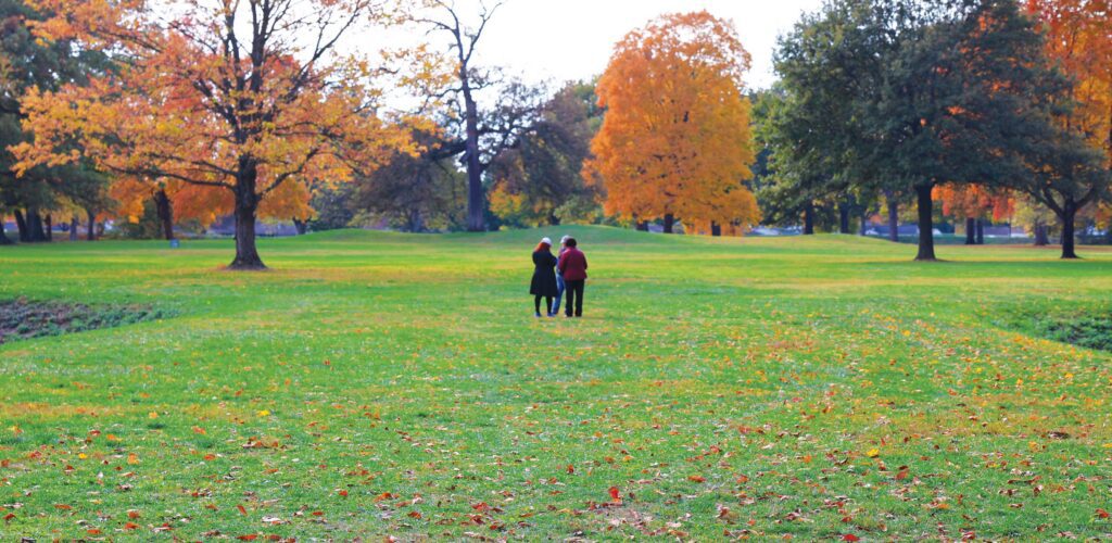 Image of three people standing in the gateway of the Great Circle Earthworks during autumn.