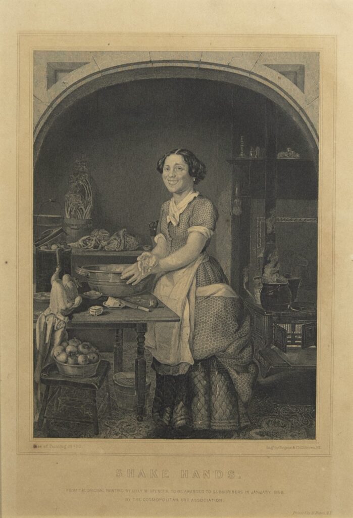 Black-and-white image of a smiling woman at work in a nineteenth-century kitchen who pauses her work to extend her dough covered hand to the viewer.