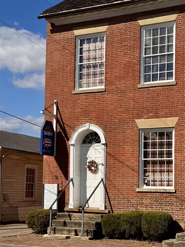 Brick building with a white door and a sign that says Our House Tavern