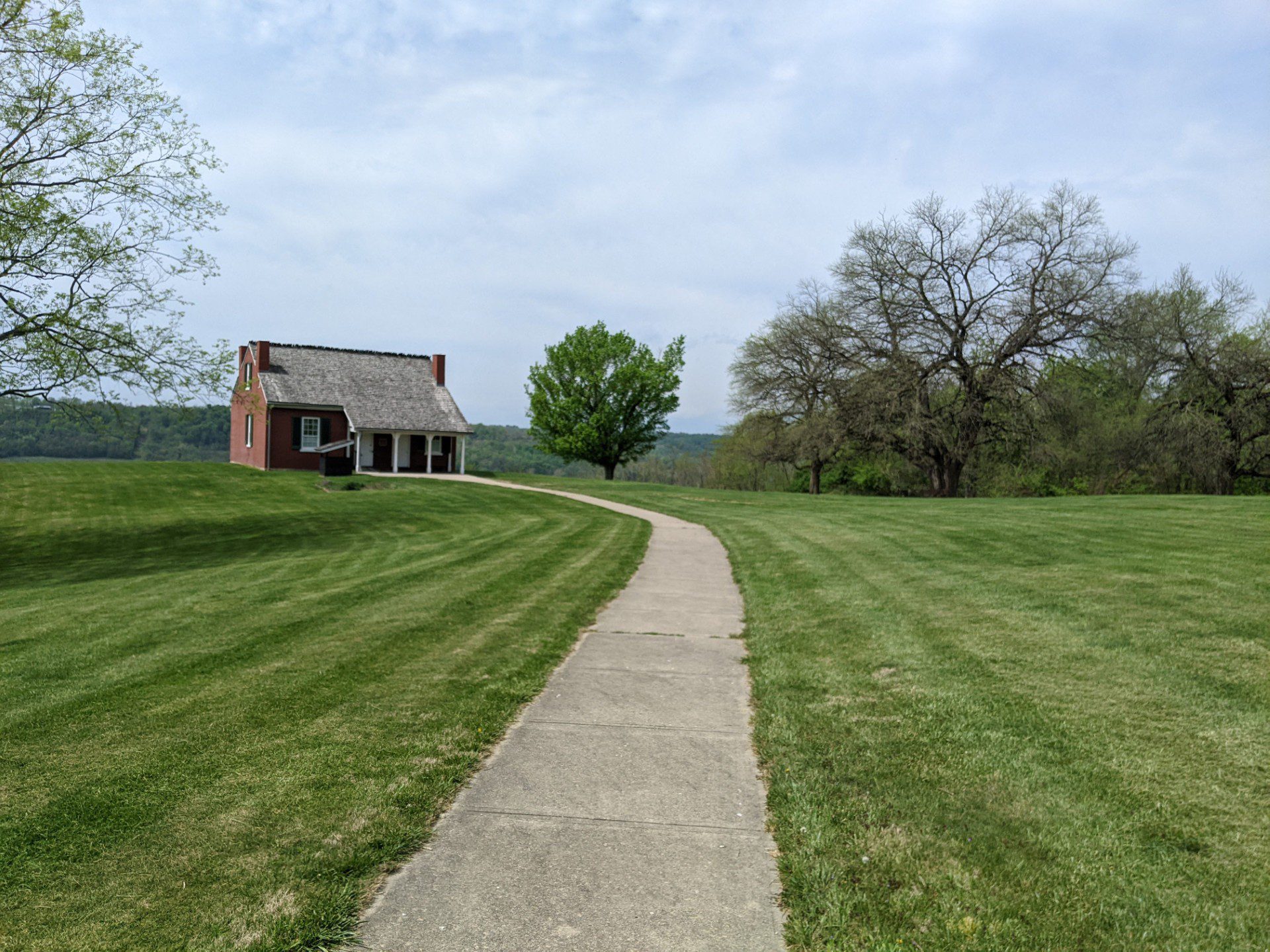Long roAD WITH LARGE GRASS LAWN ON EITHER SIDE LEADING UP TO AN OLD HOUSE