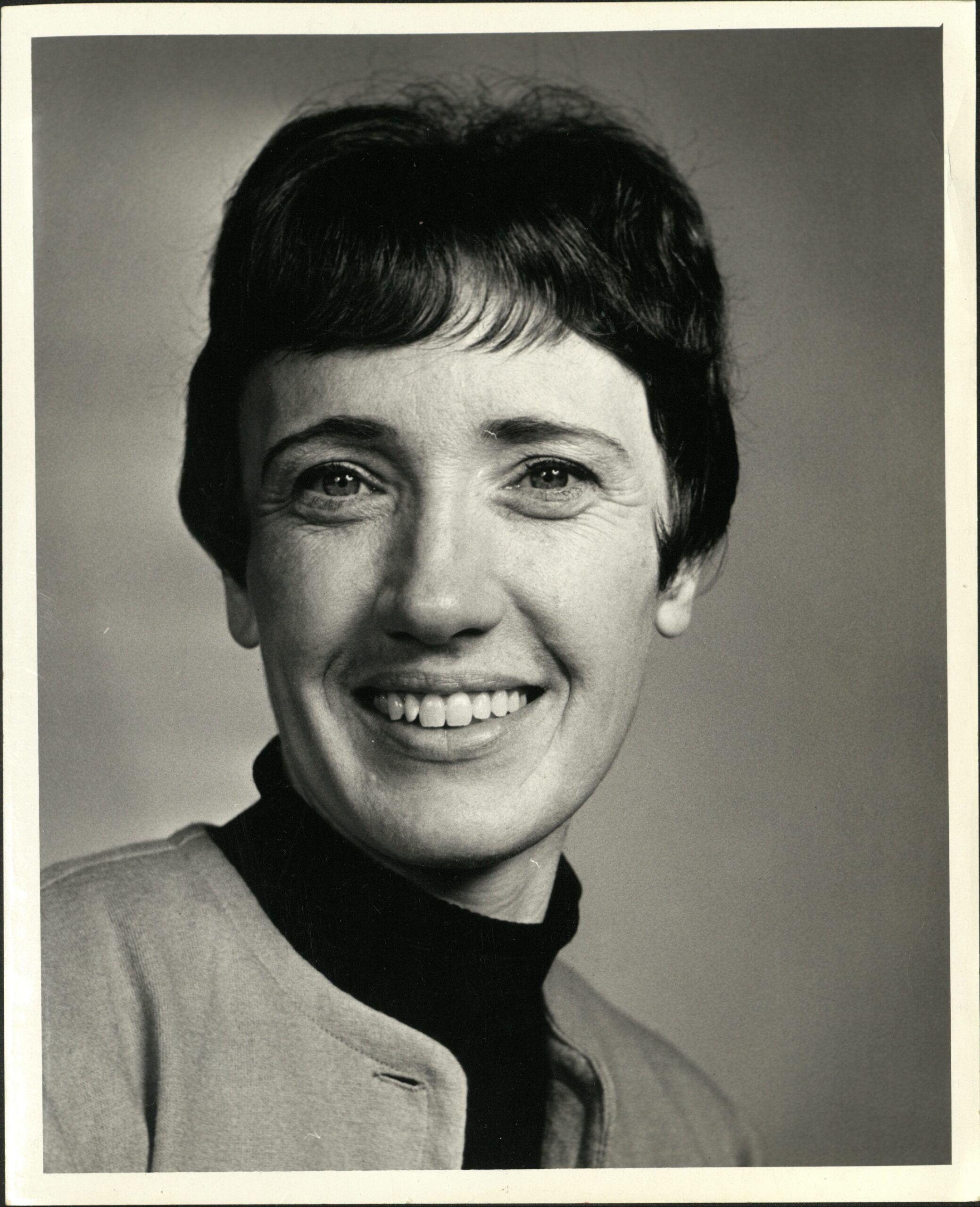 Black and white headshot of a smiling woman with short hair.