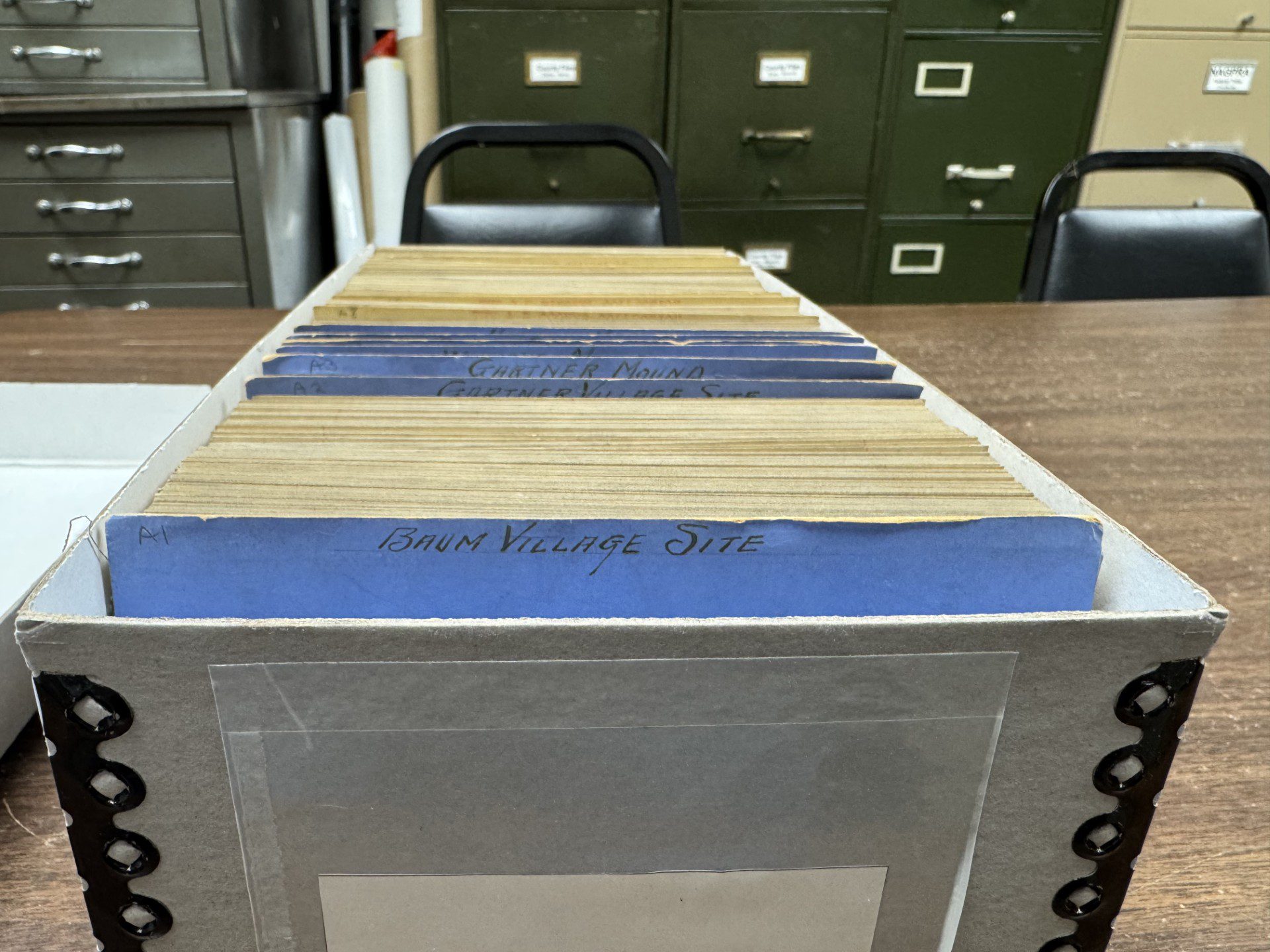 A grey archival box filled with index cards separated by blue tabs