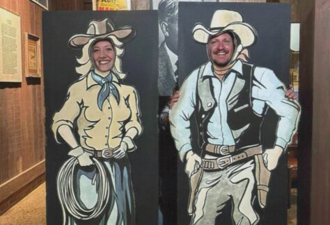 Image of a couple posing with a cutout cowboy-themed board at the National Road and Zane Grey Museum
