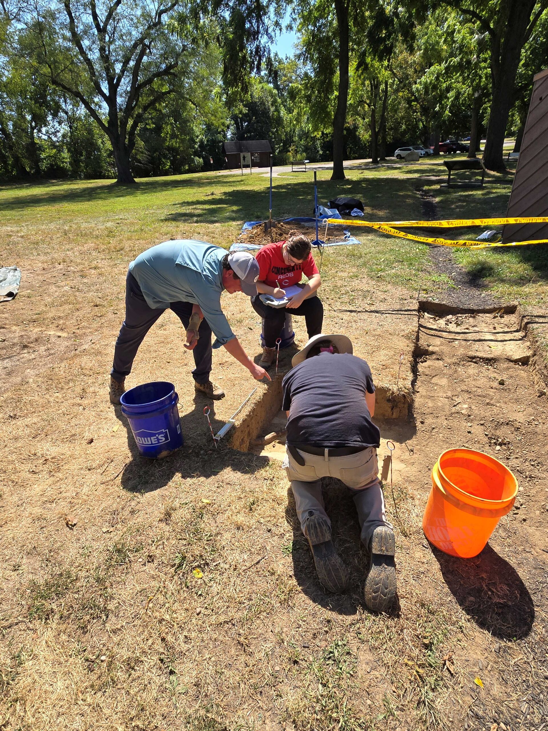 Crew (Peter Ellis standing, Hope Scott sitting, Owen Dimali excavating) working on a portion of the western fort wall during archaeology excavation at Fort Laurens in 2025.