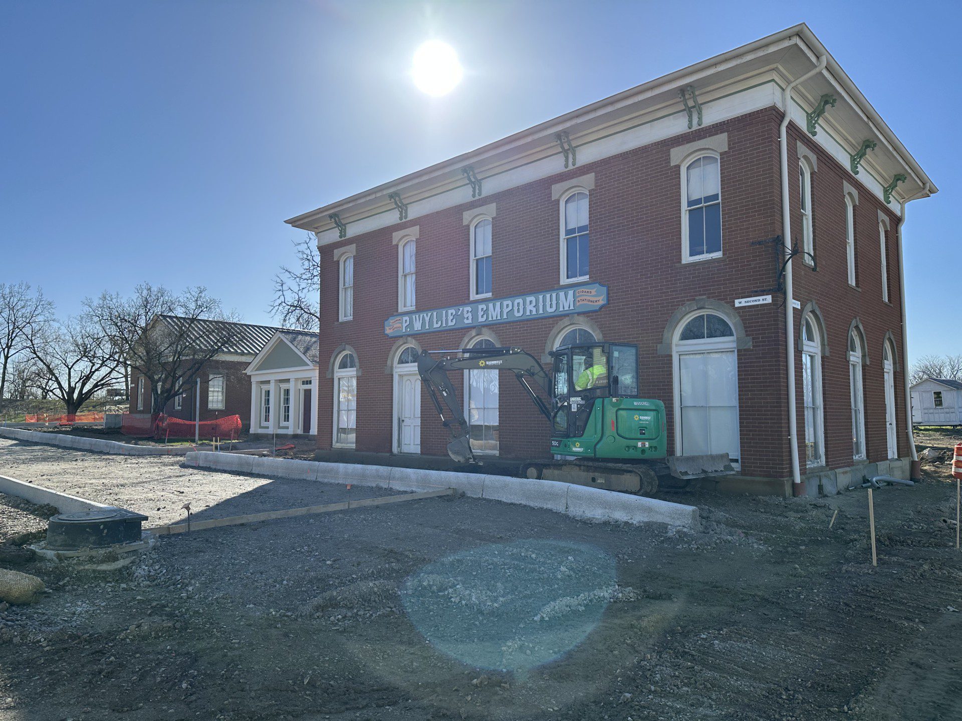The morning sun shines over the Emporium building with a construction vehicle in the foreground.